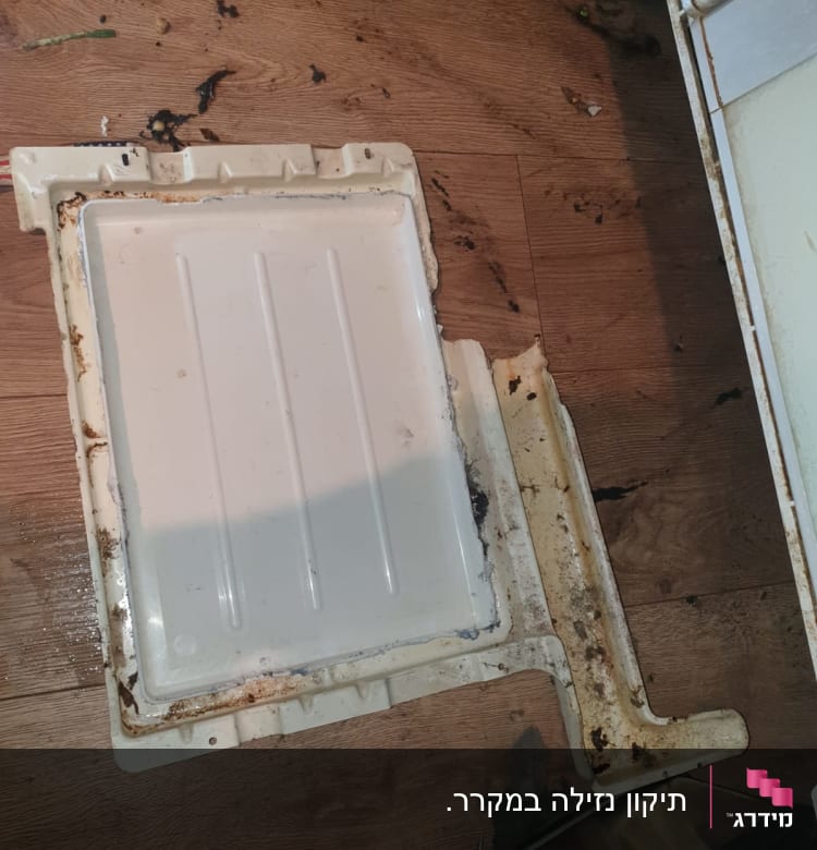 חלק פלסטיק מלוכלך של מקרר על רצפה